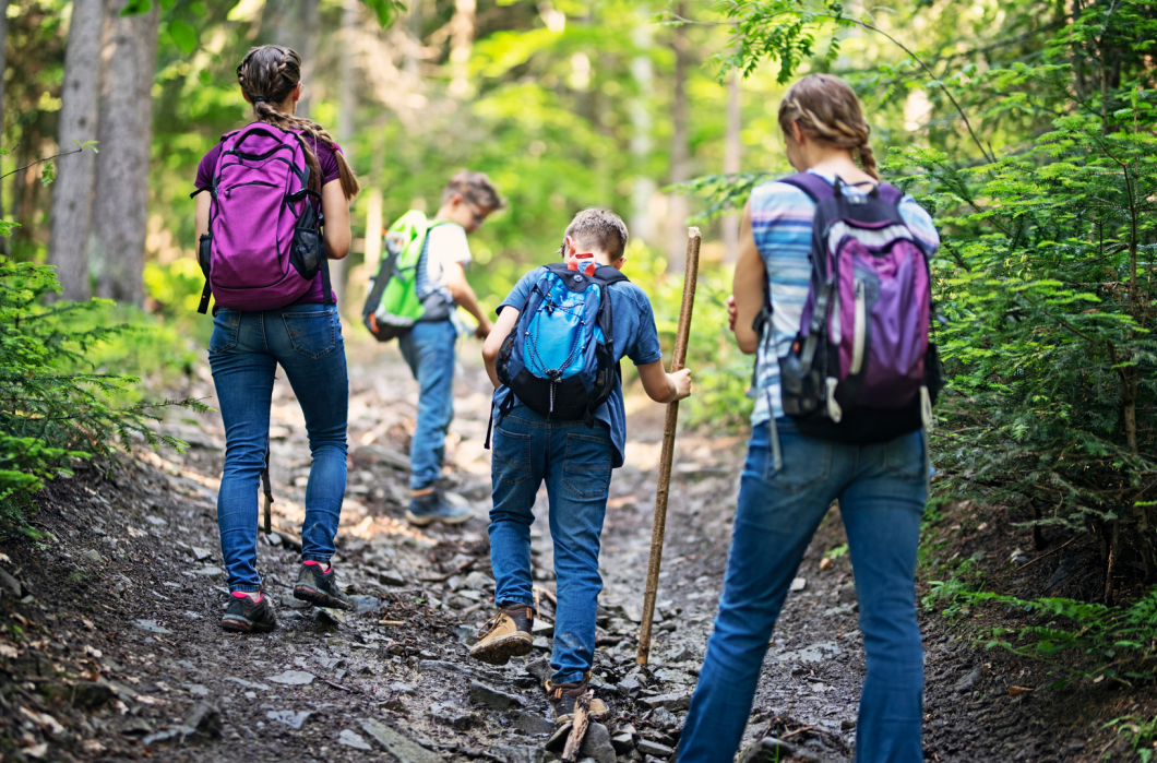 children at outdoor activity with backpacks walking